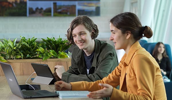 two young people work on laptops in a modern building