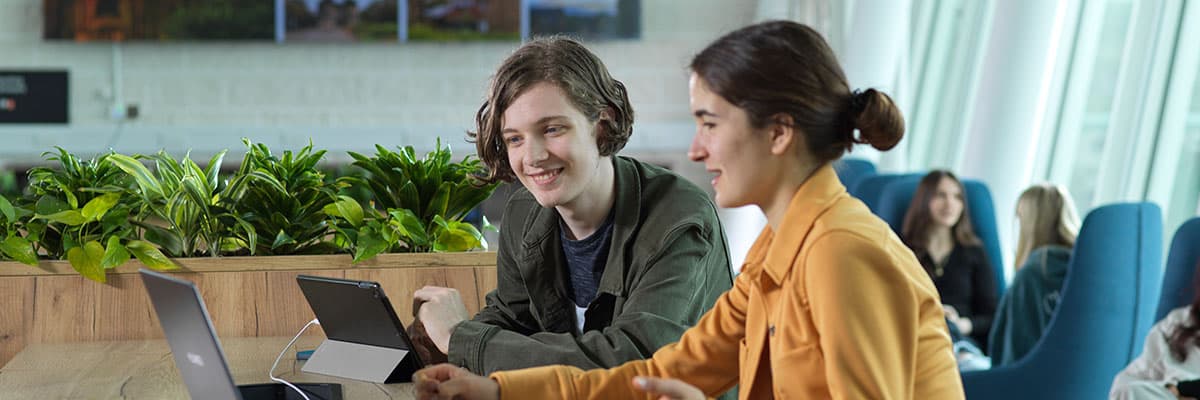 Two students with a laptop in a bright modern study space