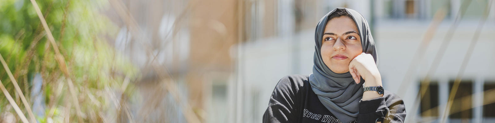 A student stands in the sunshine near the LICA building