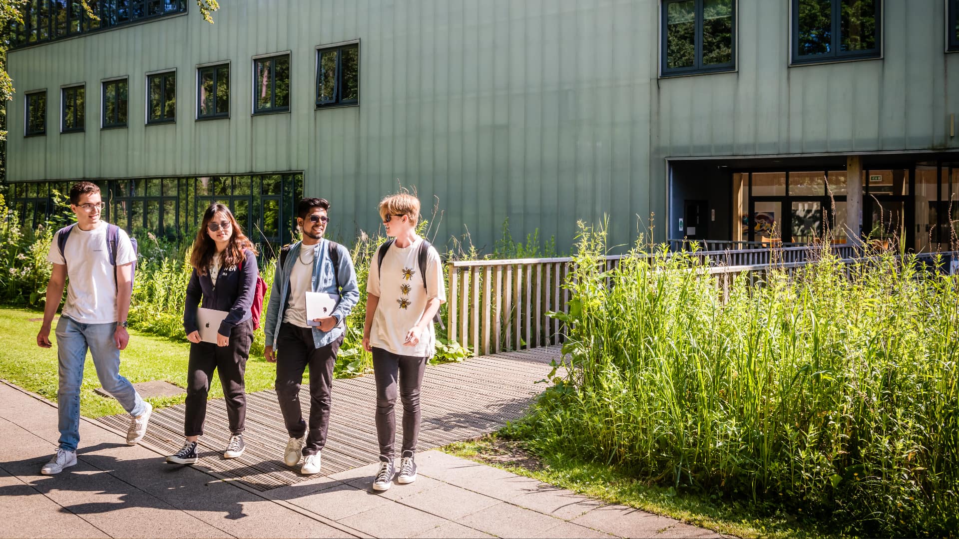 Four students walk across the green campus