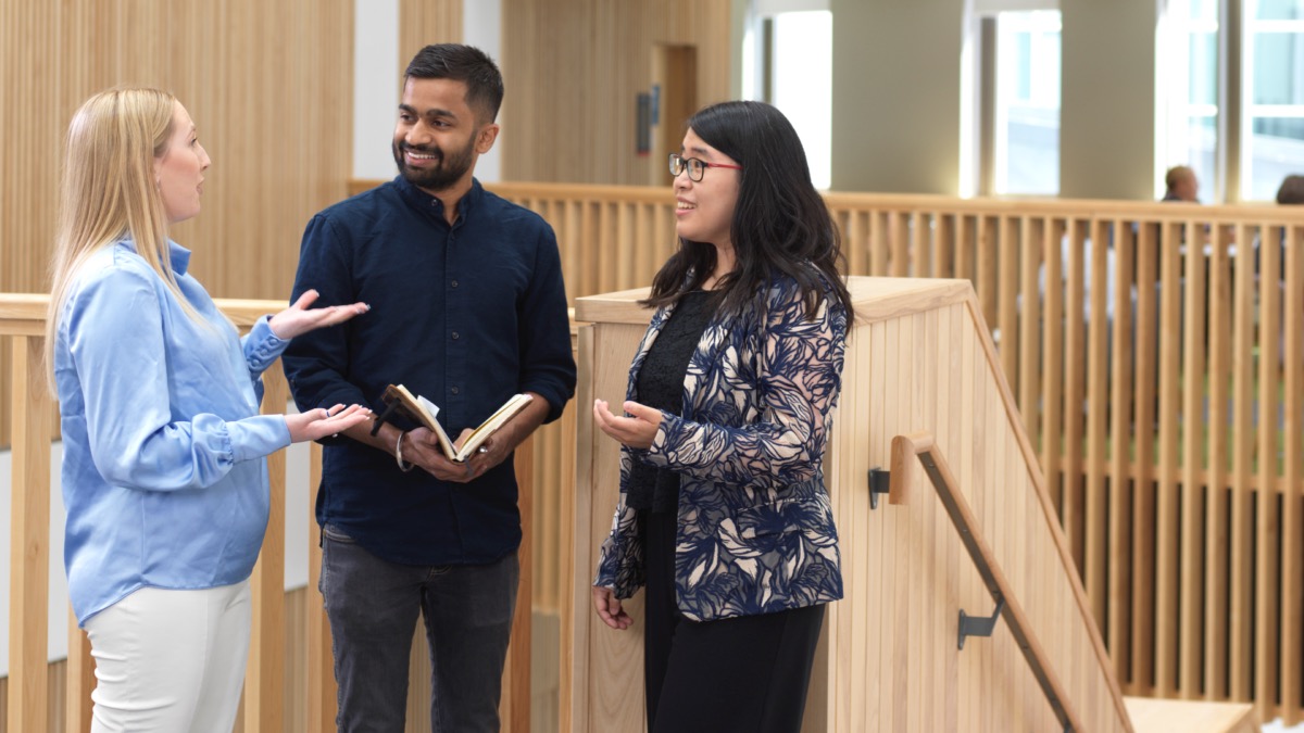 A member of staff talks to two students in the LUMS West Pavillion