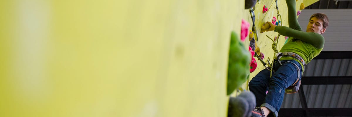 A person is high up on a climbing wall in the Lancaster University sports centre.