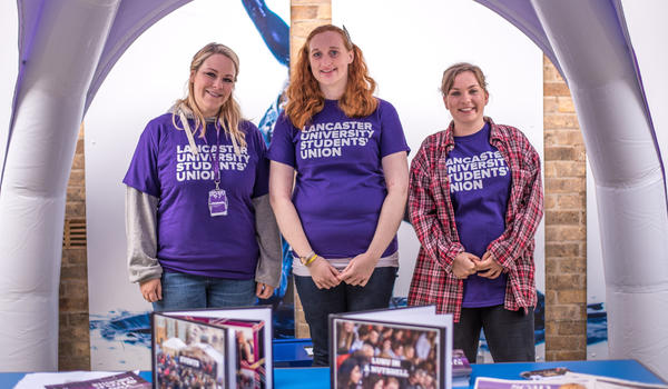 Three female students wearing purple students union t shirts