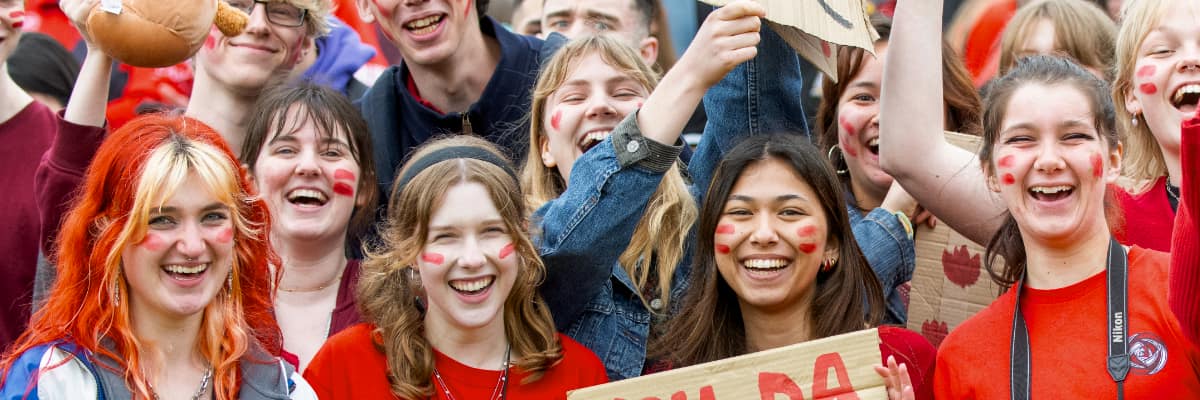 A crowd of students in red cheer on Lancaster at a Roses tournament
