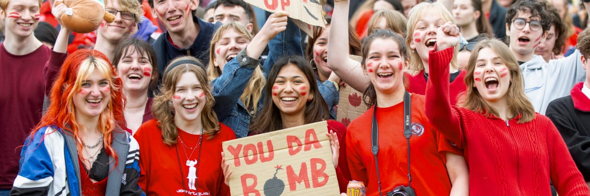 A crowd of students in red cheer on Lancaster at a Roses tournament