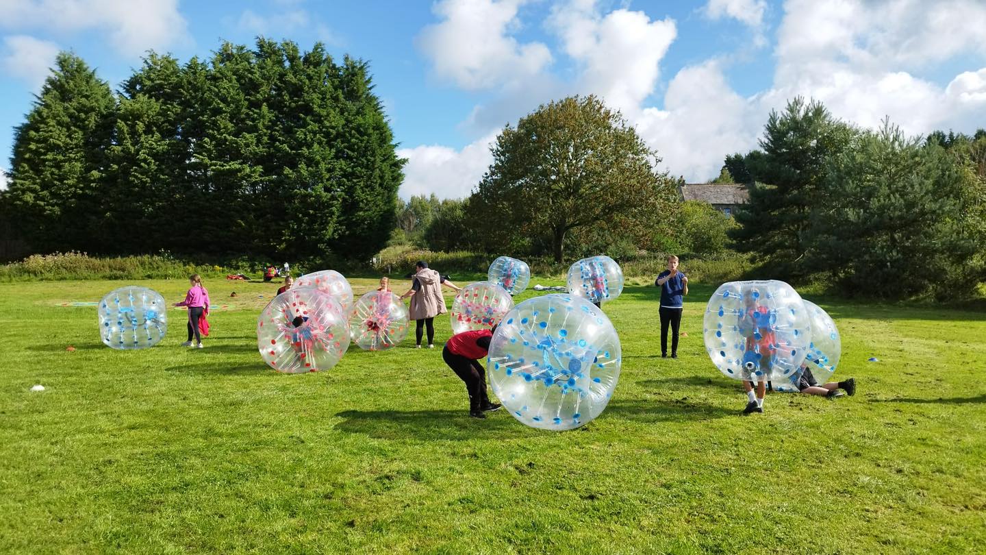 Children zorbing on a grassy field