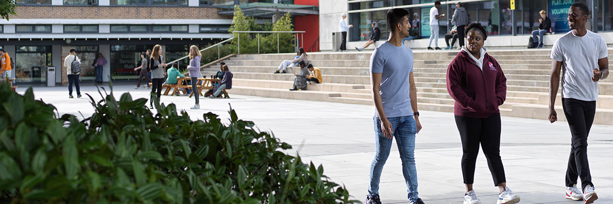 Three students walking in an open Square on campus