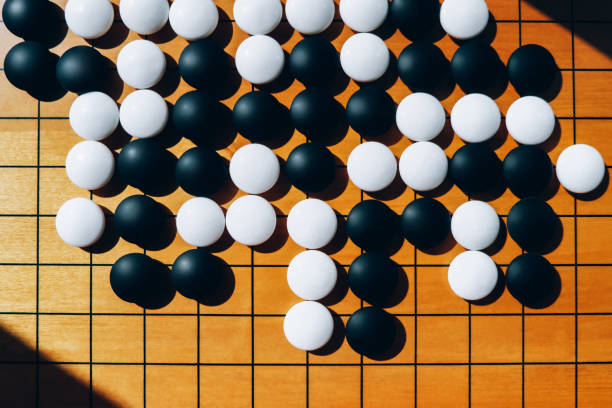 Close Up Wooden Board For Playing Go With Black And White Stones On Shadow