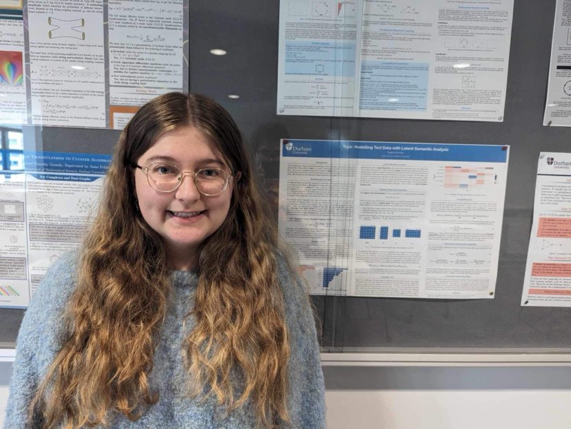 Sophie smiling in front of Master's poster.