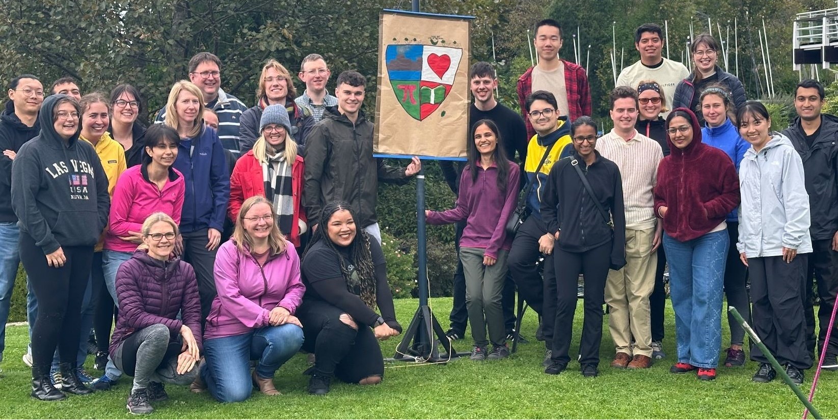 STOR-i staff and students outside by a painted shield smiling.