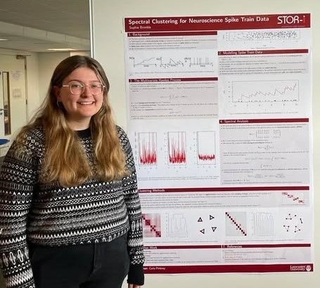 Sophie smiling in front of STOR-i internship poster.